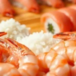 Close-up of a sushi platter featuring shrimp, rice, and sushi rolls.